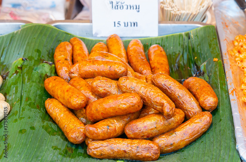 Sai Oua (Sausage), a traditional northern Thai food, placed on fresh banana leaves, sold in local markets with price labels. photo