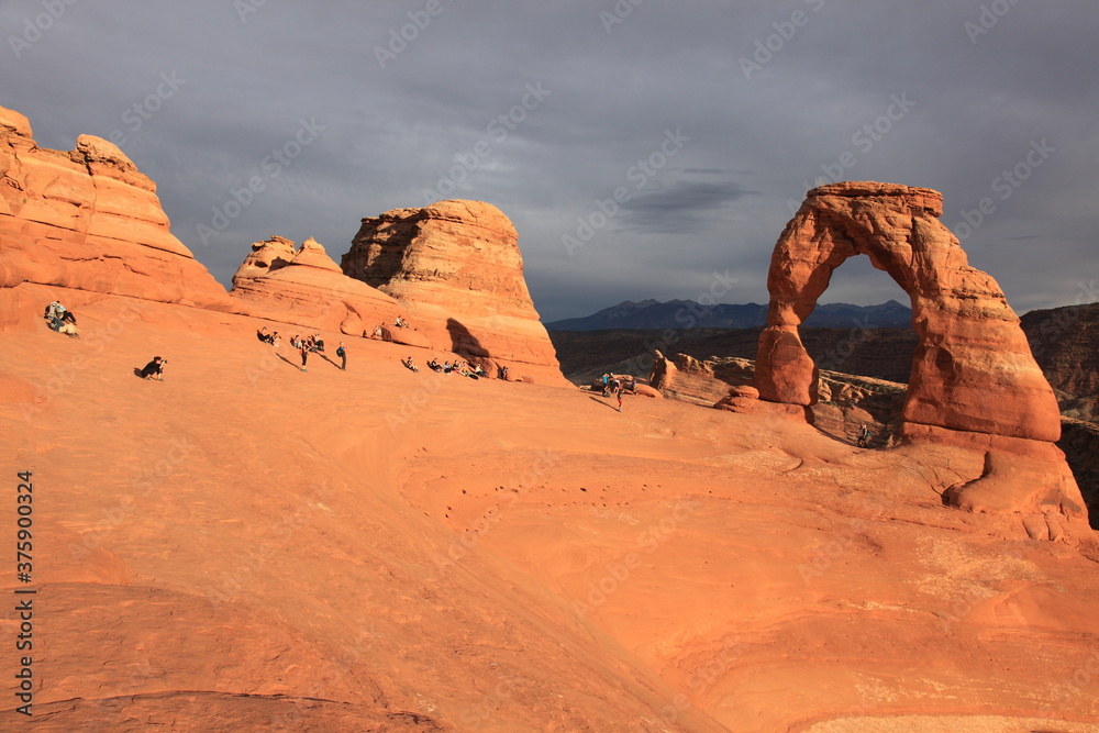 Tourists visiting and taking pictures of Delicate Arch at Sunset in Arches National Park Utah, USA