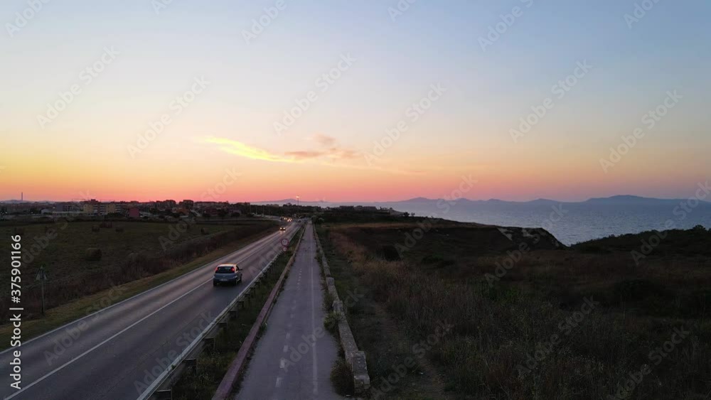 View from above, stunning aerial drone view of a road that runs along a rocky coast bathed by a turquoise and transparent sea in Sardinia, Italy View from above, stunning aerial drone view of a road that runs along a rocky coast bathed by a turquoise and transparent sea in Sardinia, Italy