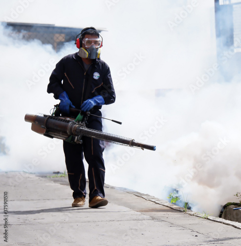 Outdoor health workers in protective clothing using chemical fogging machines to kill mosquitoes.