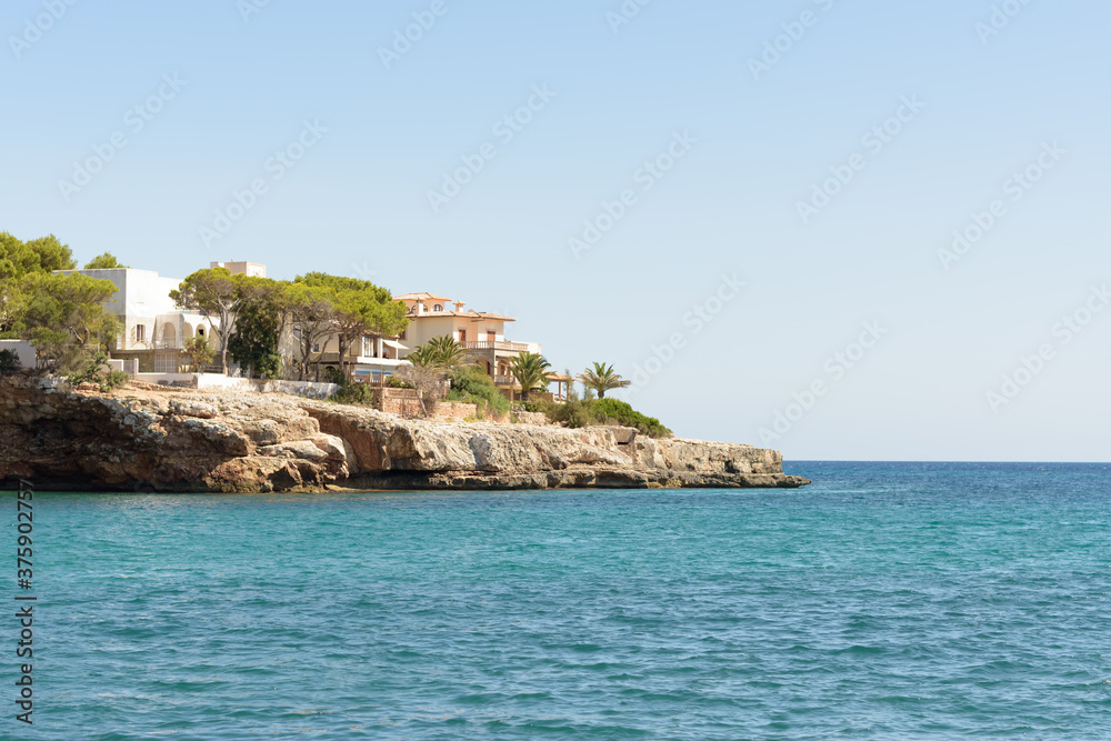 Private Mediterranean coastal villas looking onto calm turquoise water on a sunny summer day