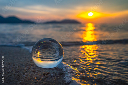Close-up of glass ball in beautiful sunset beach with bokeh background