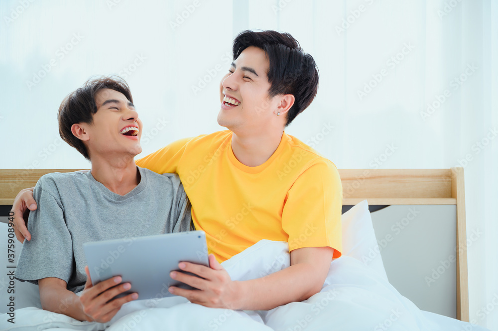 Banner happy gay couple homosexual happiness lifestyle on bed in cozy home bedroom. Two young best friend talk, hug, dance happy and laugh together relation fall in love. LGBTQ relation concept