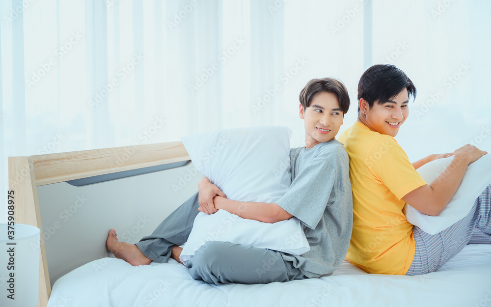 Homosexual men or gay couples with pillows battle on the bed on bedroom morning Homosexual men or gay couples with pillows battle on the bed on bedroom morning