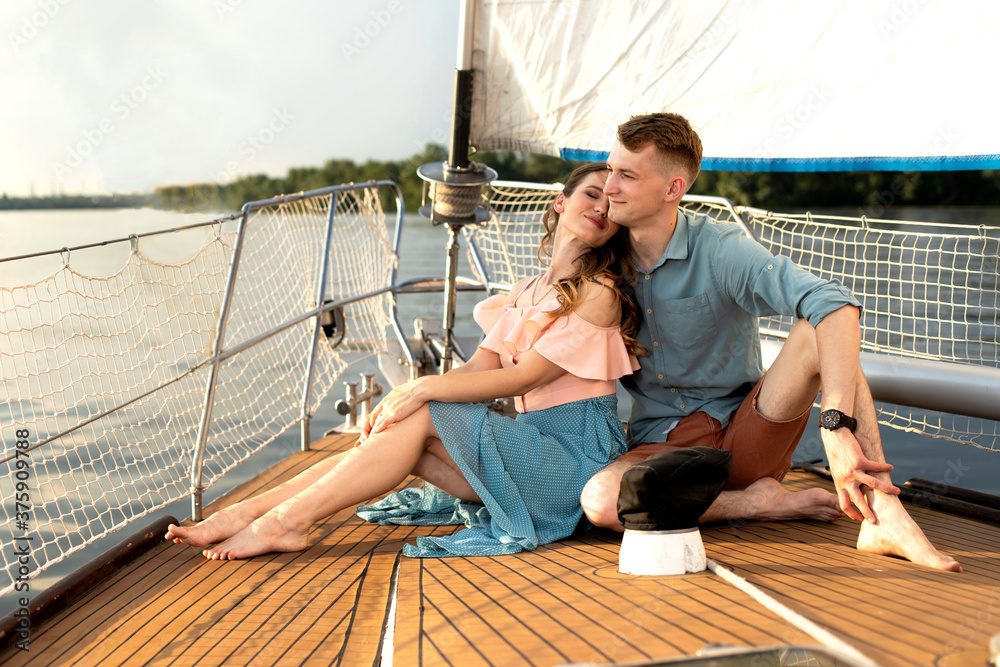 Young loving couple resting on the deck of the yacht