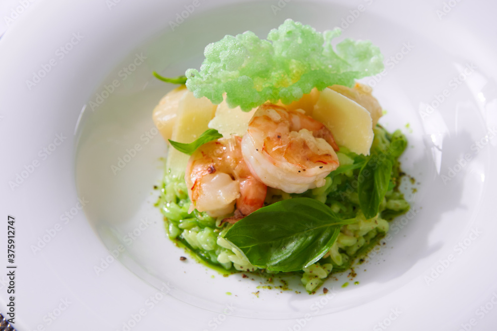 Delicious risotto with spinach, greens and prawns. Served in a modern dishware. Shallow dof Delicious risotto with spinach, greens and prawns. Served in a modern dishware. Shallow dof