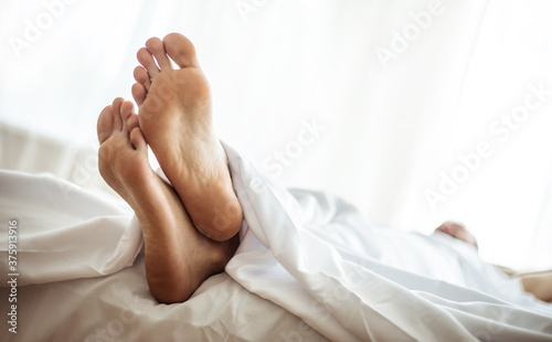 Close up photo of Young male legs under blanket in the bedroom
