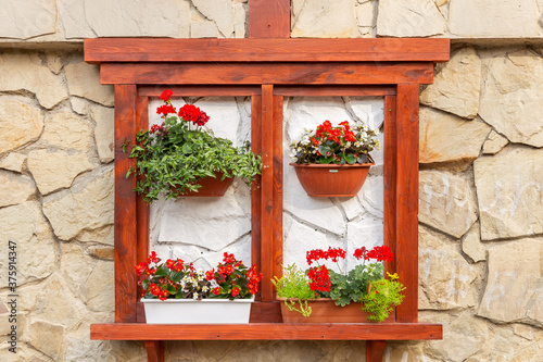 Decoration on the facade of the house of pelargonium and begonia flowers in a pot. Floral decoration on the wall.