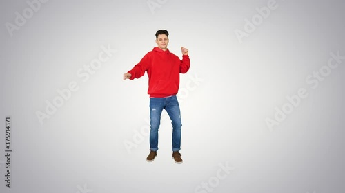 Hip-Hop style man in red hoody dancing on gradient background. photo