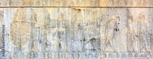 Photos Bas-relief on the southern wall of the east stairway of the Apadana in Persepolis:Scythian tribute bearers, armed and wearing distinctive headgear, offering a bracelet and folded coats and trousers