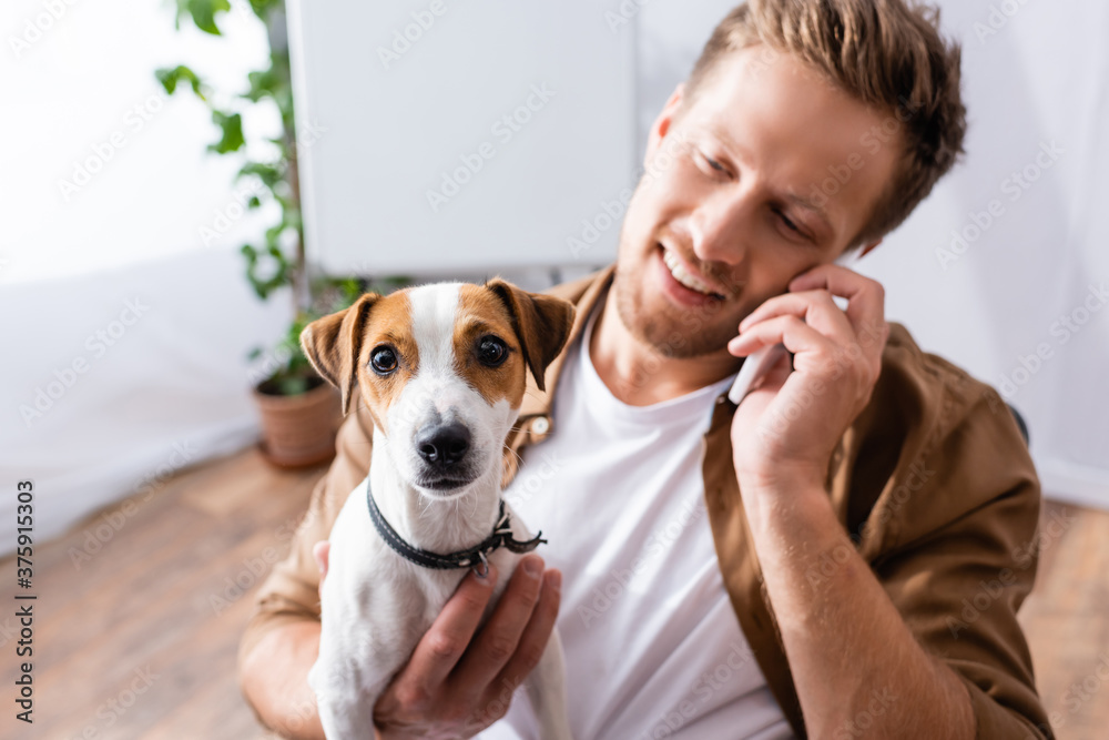 selective focus of businessman talking on mobile phone while holding jack russell terrier dog