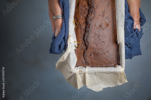 Hands with a blue cloth carrying a mold with sponge cake fresh from the oven, Overhead view photo