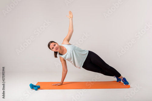 a woman makes a side plank and looks at the camera on a white background with space for text