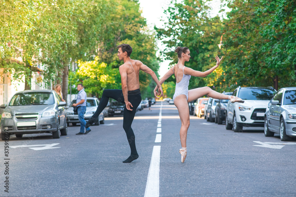 Ballet couple dancing on the road among cars