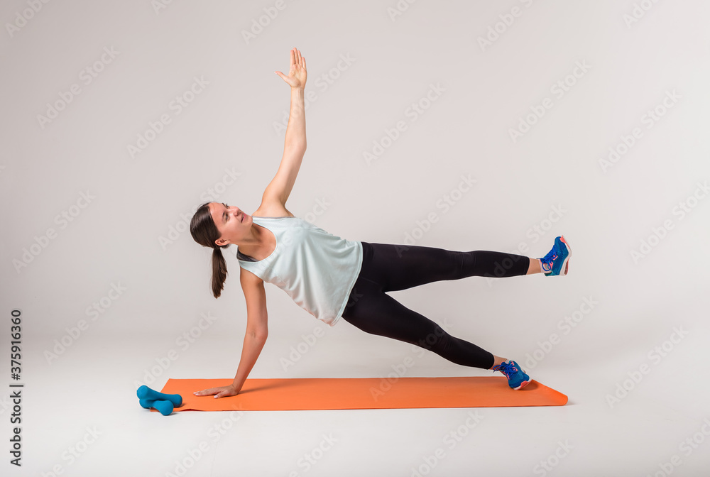 a woman performs the exercise side plank and looks up on a white background a woman performs the exercise side plank and looks up on a white background