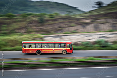 Red colored old Pune Municipal transport local bus , speeding on highway.