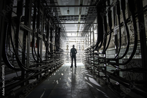Fotografie Silhouette of a man with a lantern in a dark cable tunnel with many cables