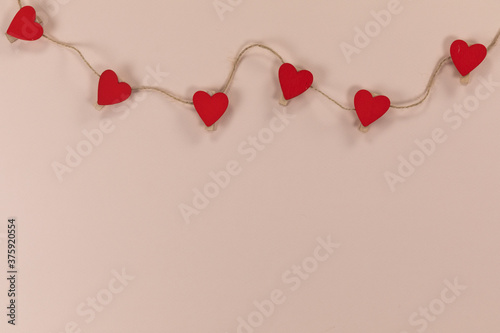 View of a heart necklace held by brown thread on pink background