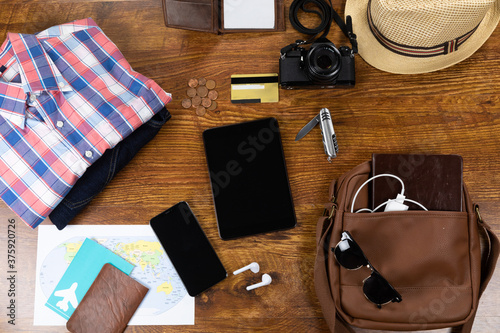 View of a variety of essential travelling items with tablet, smartphone and camera on wooden table
