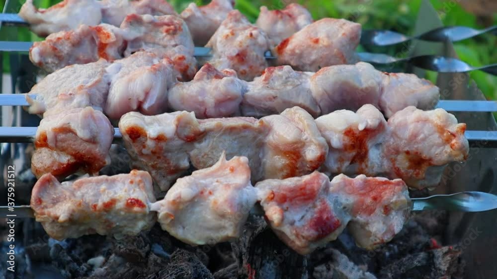 Shish kebab on metal skewers is slowly cooked over hot coals. Close-up Shish kebab on metal skewers is slowly cooked over hot coals. Close-up