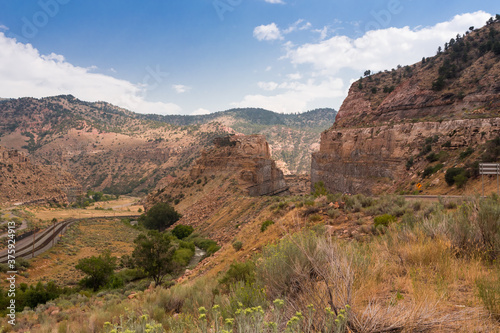 Price river valley in Utah, USA. Orange sandstone geological formations frame railroad and water stream
