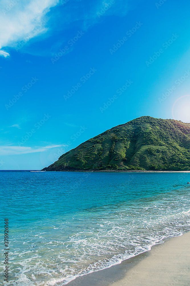 Mar verde y azul transparente con una montaña de fondo