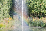 Rainbow reflected in the water of a fountain and surrounded by trees and a lot of vegetation in Landgraaf, South Limburg the Netherlands Holland