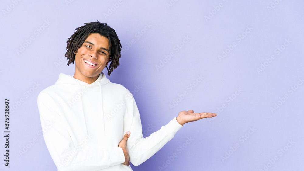 Young african american rasta man showing a copy space on a palm and holding another hand on waist. Young african american rasta man showing a copy space on a palm and holding another hand on waist.