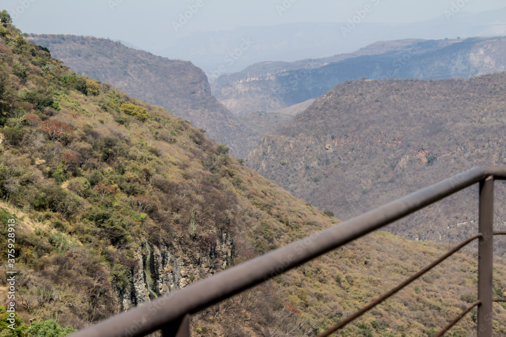 Huentitan canyon on a wonderful day with a gray sky seen from a viewpoint with a metal fence in Guadalajara Jalisco Mexico Huentitan canyon on a wonderful day with a gray sky seen from a viewpoint with a metal fence in Guadalajara Jalisco Mexico