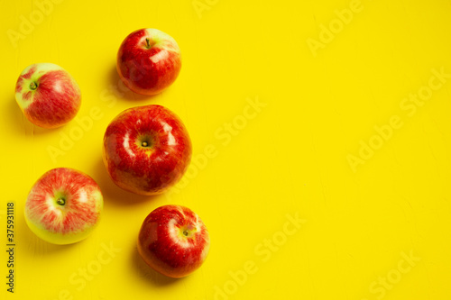 Red ripe apples on a yellow background. Copy space. Top view
