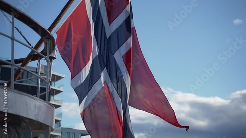 Official Norwegian national flag waving in the wind with blue skies in the background.