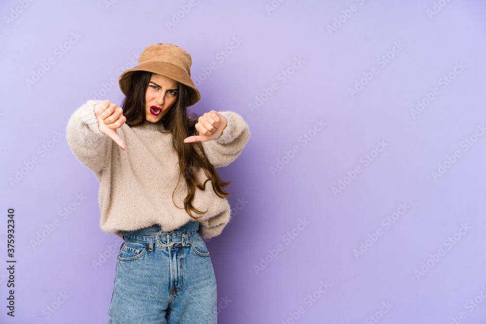 Young caucasian woman isolated on purple background showing thumb down and expressing dislike. Young caucasian woman isolated on purple background showing thumb down and expressing dislike.