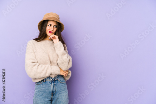 Young caucasian woman isolated on purple background thinking and looking up, being reflective, contemplating, having a fantasy.