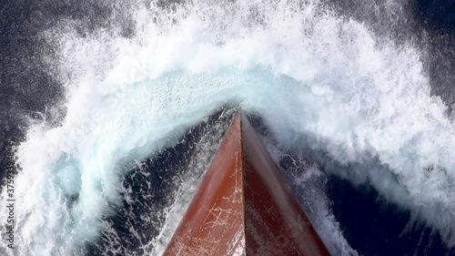 Red scratched bow of a cargo ship breaking the waves.