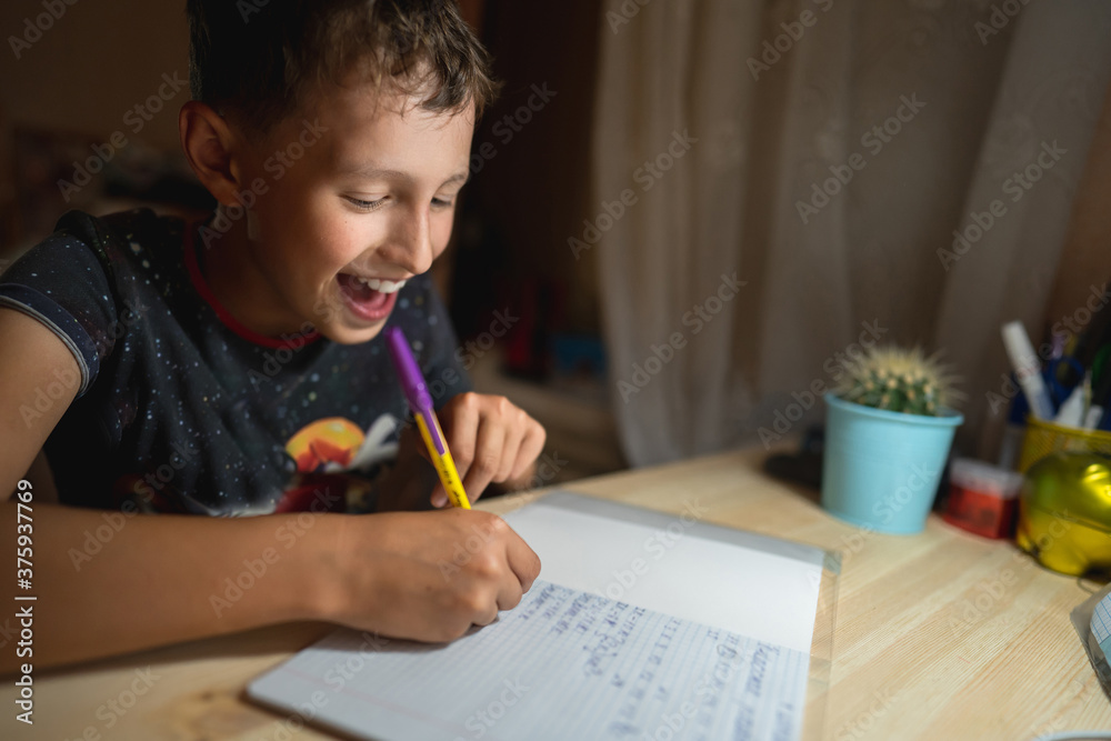 capable schoolboy of 8 years old, writes enthusiastically at the table. capable schoolboy of 8 years old, writes enthusiastically at the table.