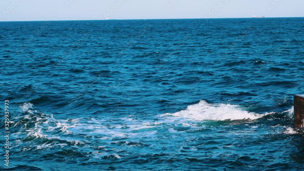 Amazing water background. Waves swaying on the sea water. Beautiful blue water waves with white foam crashing on the dock. Slow motion. Amazing water background. Waves swaying on the sea water. Beautiful blue water waves with white foam crashing on the dock. Slow motion.