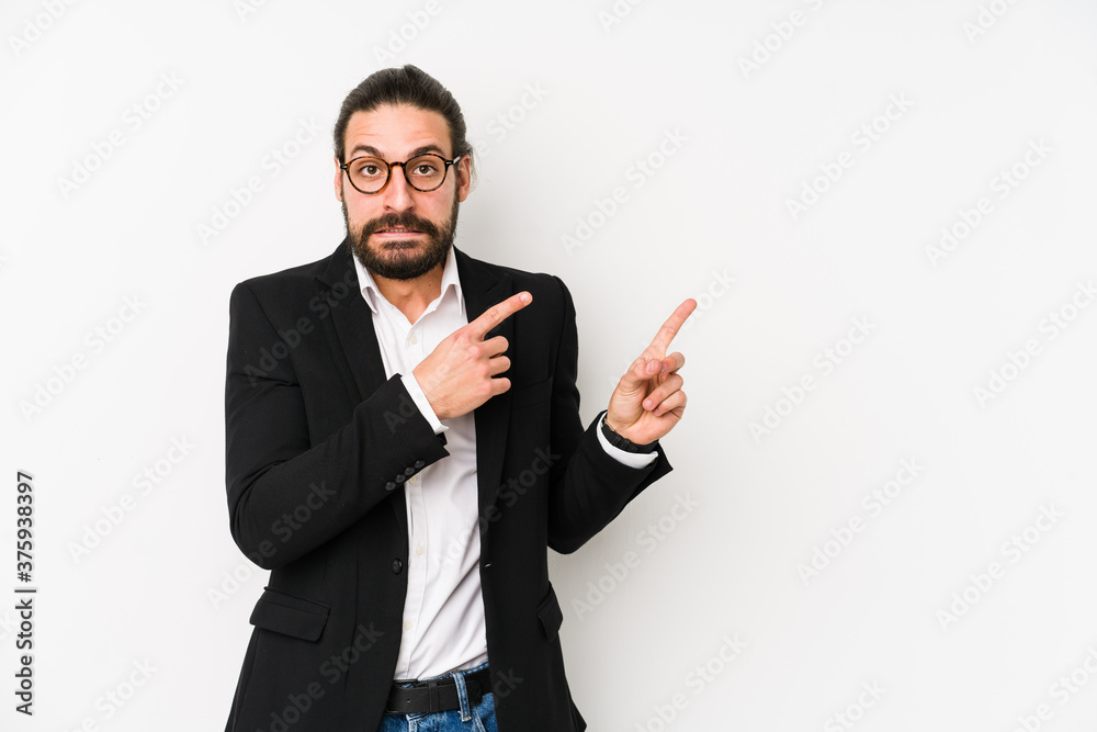 Young caucasian business man isolated on a white background shocked pointing with index fingers to a copy space. Young caucasian business man isolated on a white background shocked pointing with index fingers to a copy space.