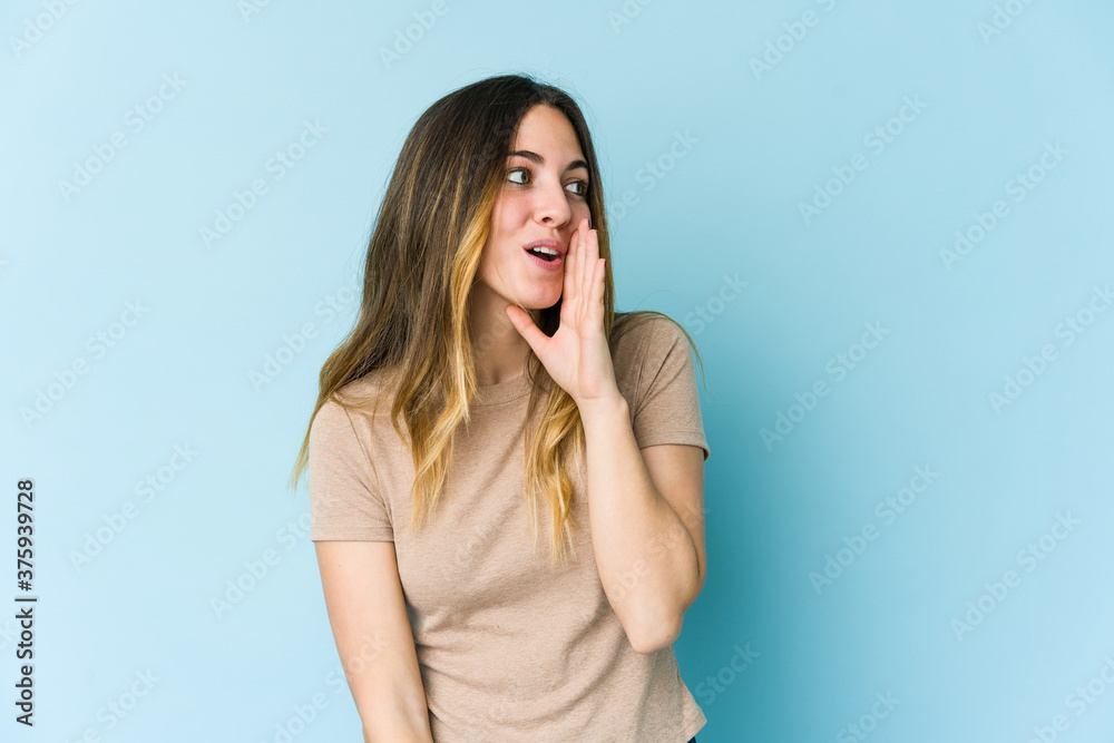 Young caucasian woman isolated on blue background is saying a secret hot braking news and looking aside Young caucasian woman isolated on blue background is saying a secret hot braking news and looking aside