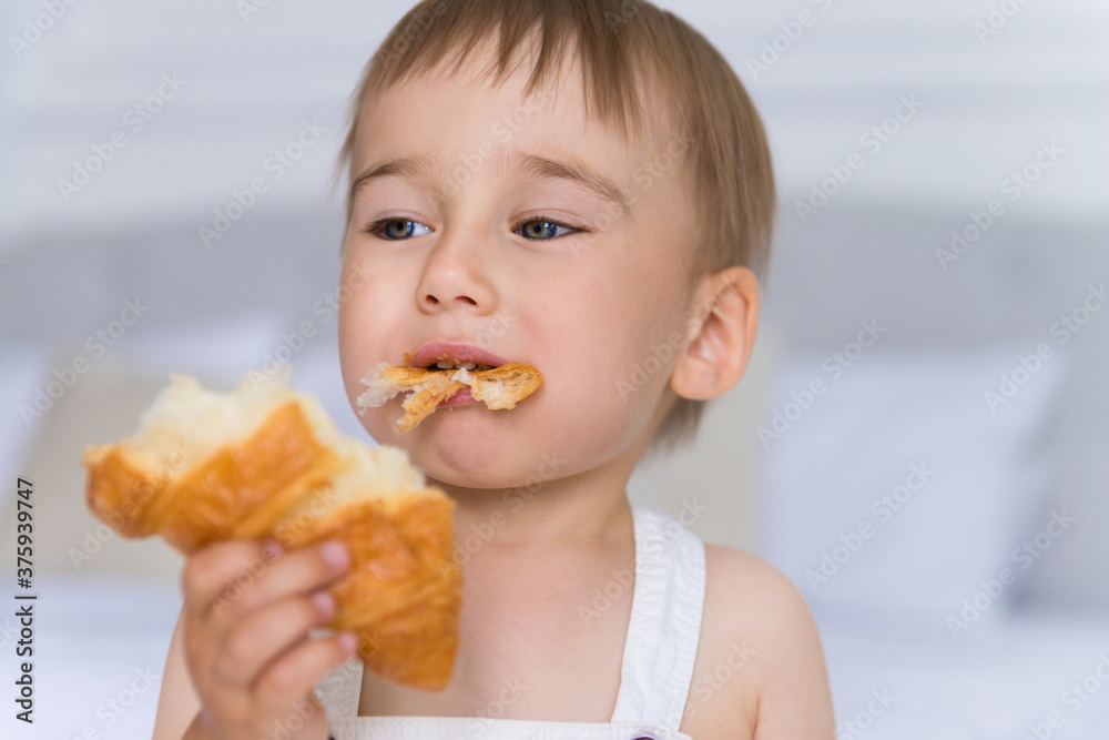happy portrait of a little smiling boy child playing and eating a croissant happy portrait of a little smiling boy child playing and eating a croissant