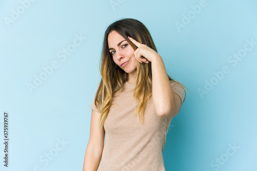 Young caucasian woman isolated on blue background pointing temple with finger, thinking, focused on a task.