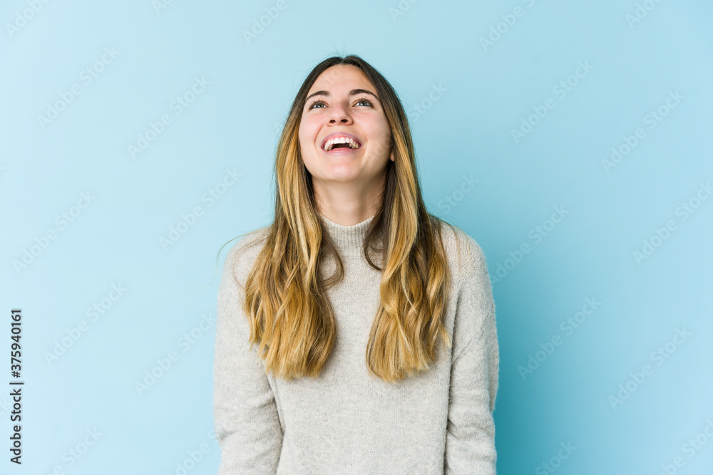 Young caucasian woman isolated on blue background relaxed and happy laughing, neck stretched showing teeth. Young caucasian woman isolated on blue background relaxed and happy laughing, neck stretched showing teeth.