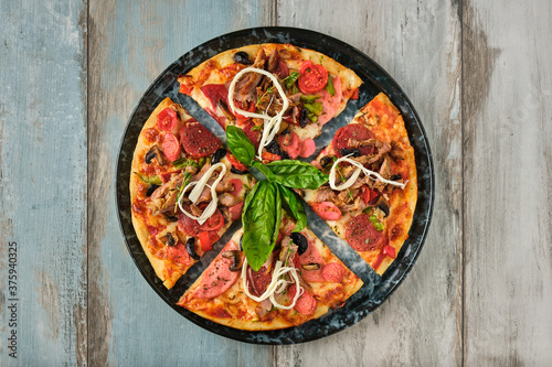 Supreme mixed pizza from top view on wooden background.