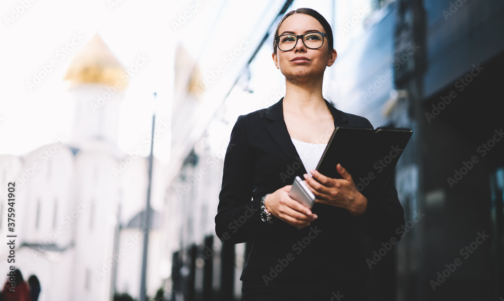 Businesswoman with folder and phone standing on street Businesswoman with folder and phone standing on street