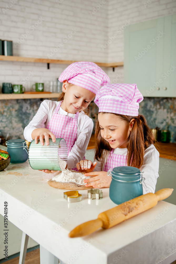 two girlfriends in the kitchen knead the dough and sprinkle flour two girlfriends in the kitchen knead the dough and sprinkle flour