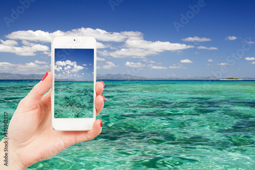 Fototapeta Naklejka Na Ścianę i Meble -  Woman holding smartphone isolated beauty landscape beach background