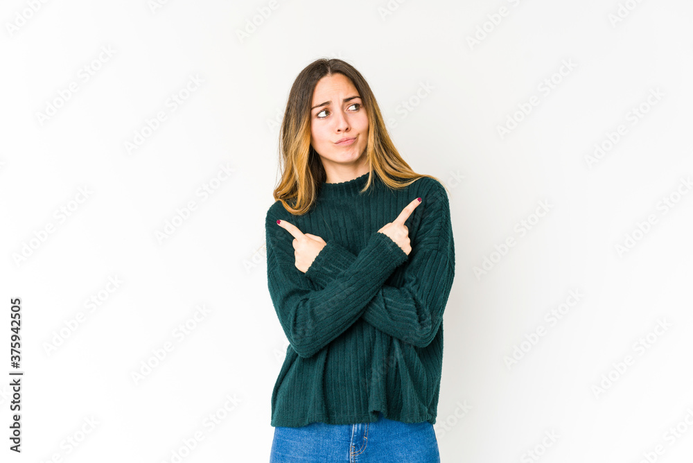 Young caucasian woman isolated on white background points sideways, is trying to choose between two options. Young caucasian woman isolated on white background points sideways, is trying to choose between two options.