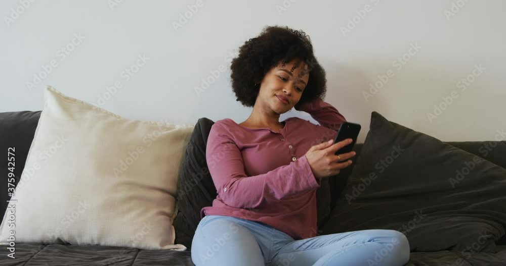 Woman using smartphone and smiling in living room Woman using smartphone and smiling in living room