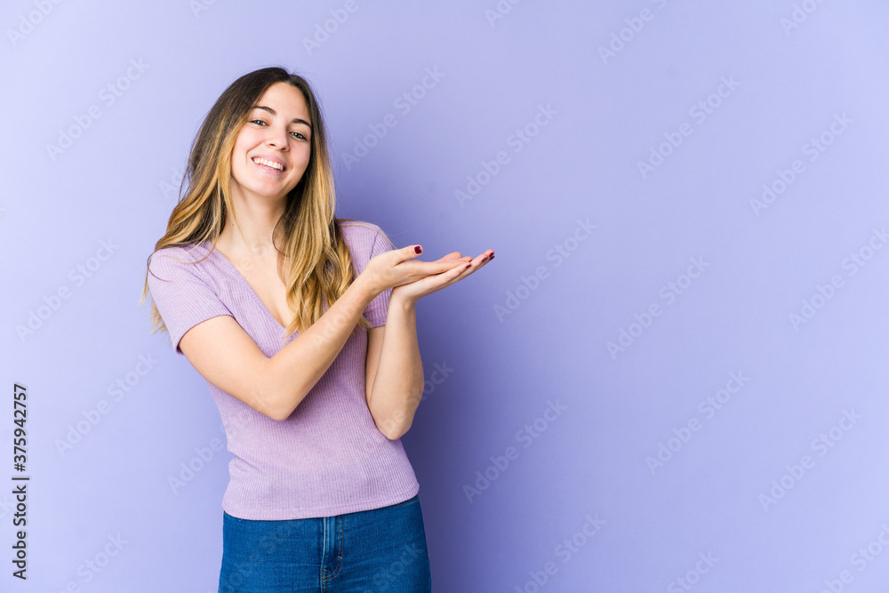 Young caucasian woman isolated on purple background holding a copy space on a palm. Young caucasian woman isolated on purple background holding a copy space on a palm.