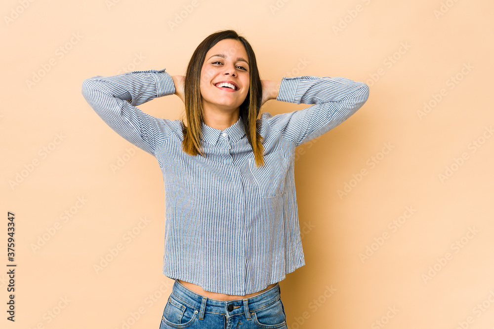 Young woman isolated on beige background stretching arms, relaxed position.