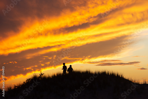 Silhouette of two people on a hill viewing a sunset